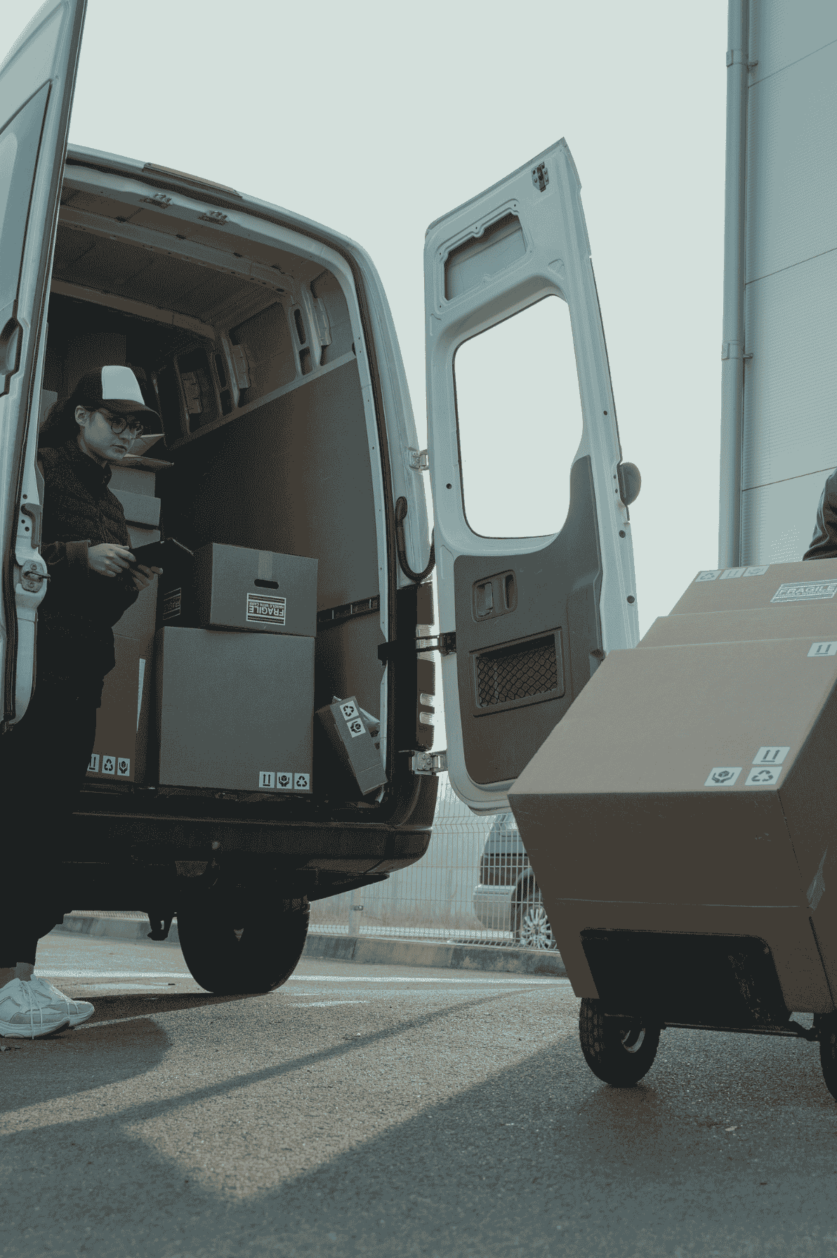 Trabajadora descargando paquetes de un vehículo ligero para reparto urbano.